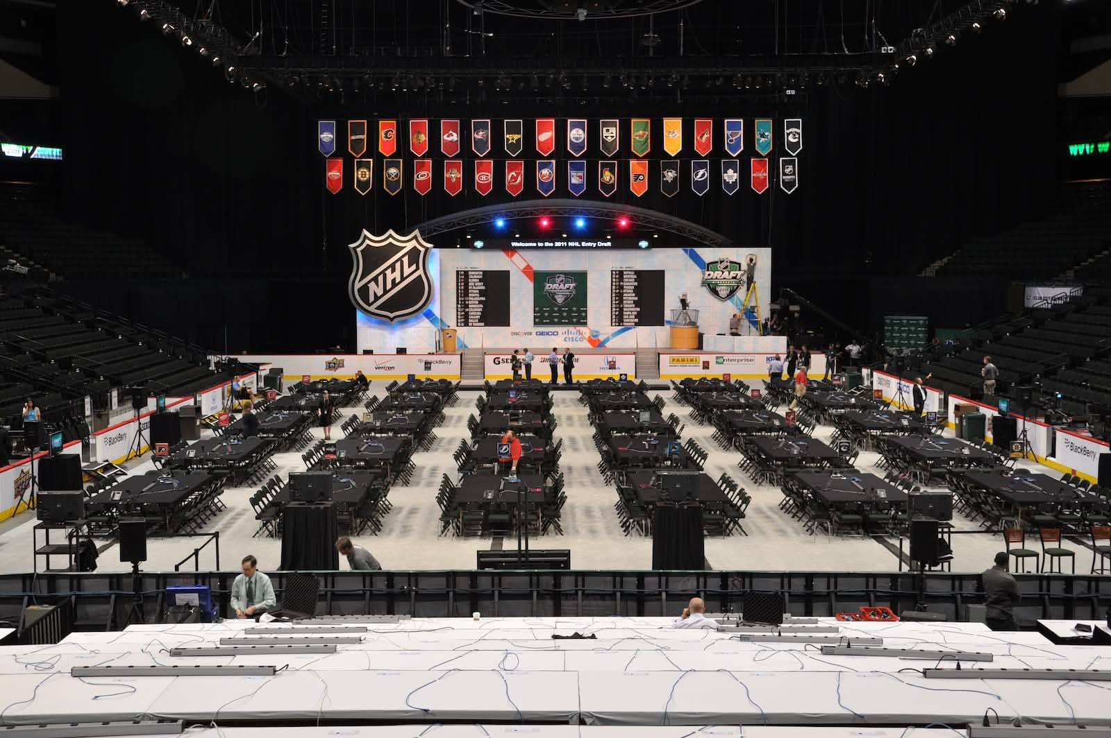 The draft floor set for round one — team banners overhead, the stage and pick board at center.